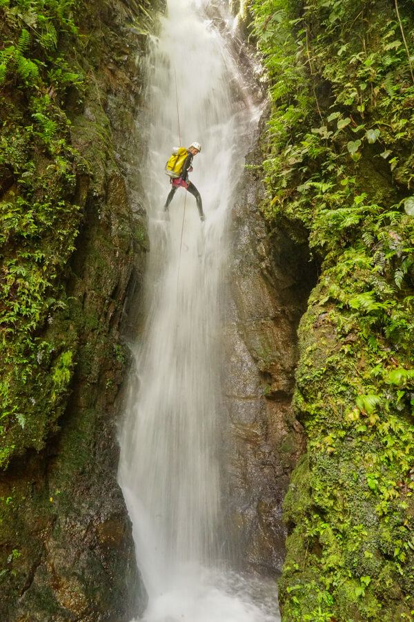 Adventure group rappelling down a jungle waterfall during a canyoning expedition near Dominical, Costa Rica