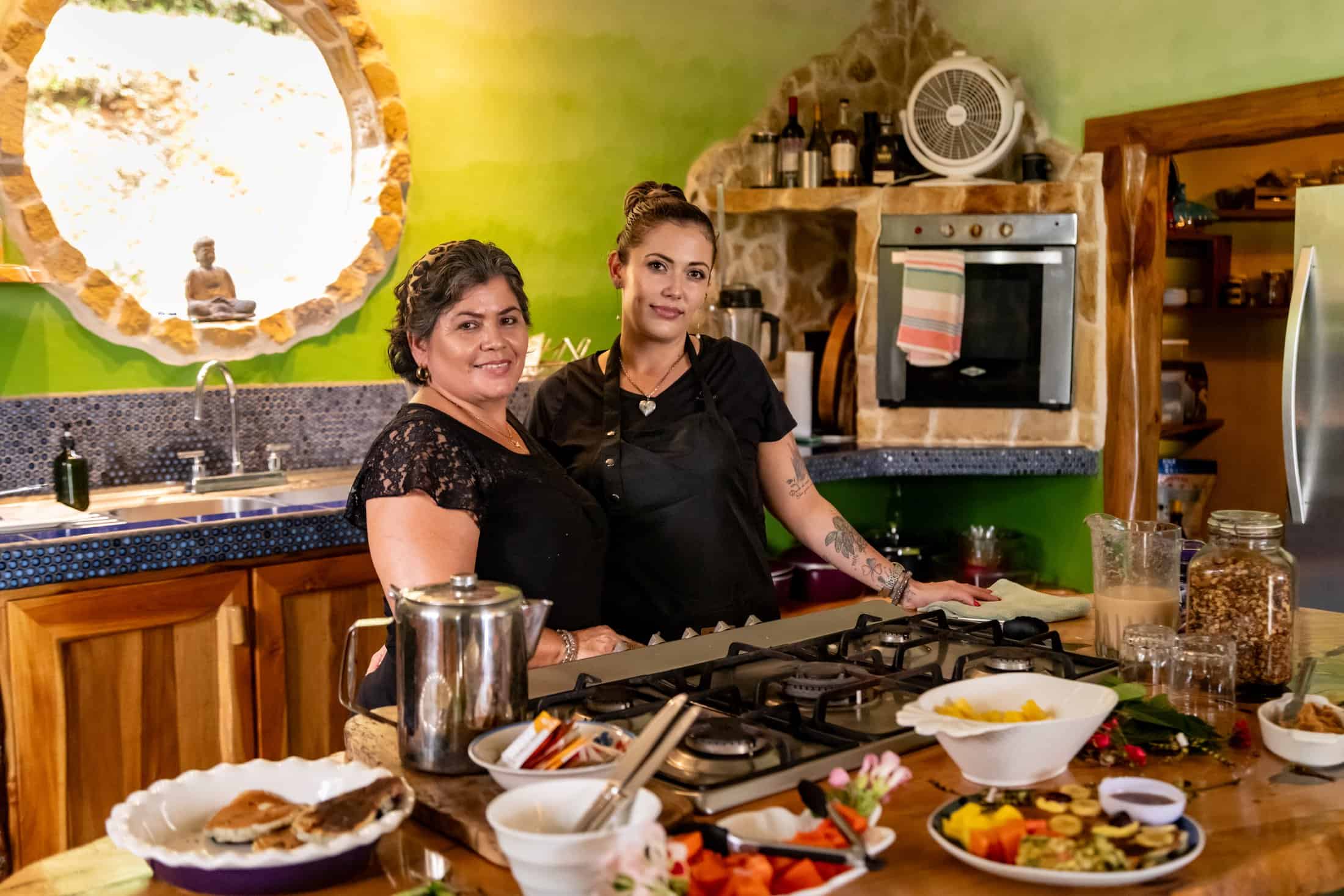 Airborne Arts in-house chef and her assistant in the kitchen, surrounded by fresh ingredients