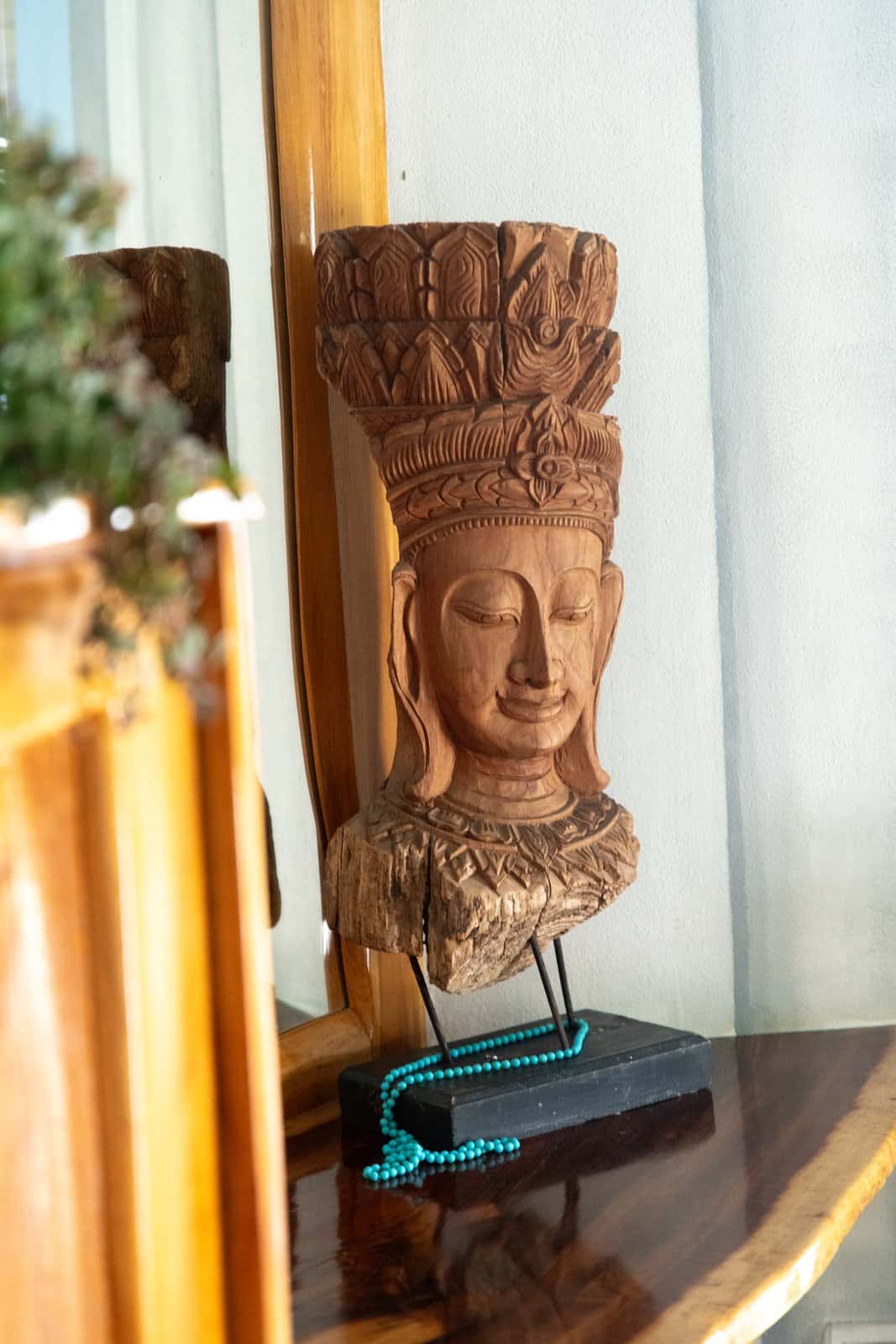 Hand-carved Buddha statue with turquoise mala beads on the dresser in the Master Suite