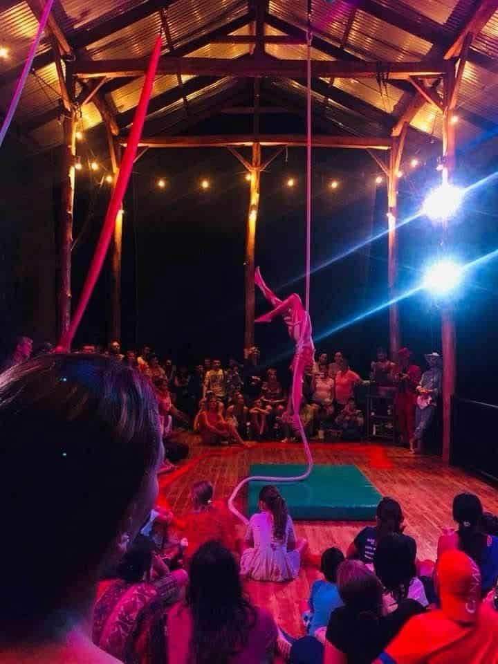 Live aerial performance at Airborne Arts with audience watching a silks act under string lights