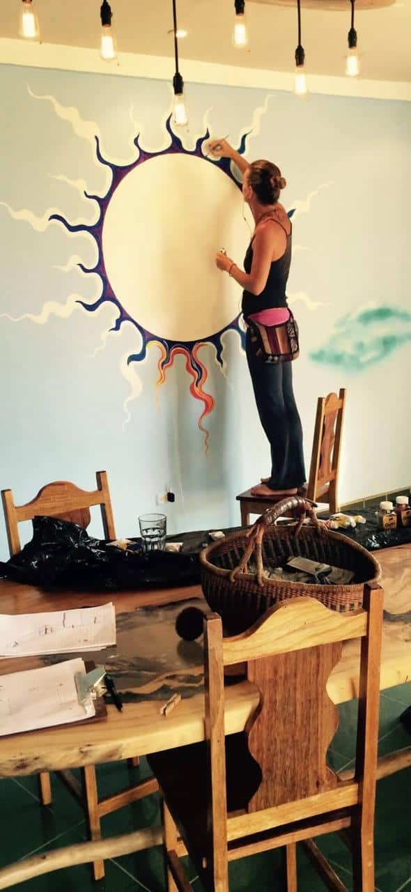 Chanti Lee painting a vibrant sun mural